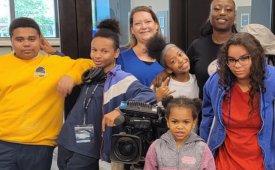 Copyright 2024 Digital Bridges International. All rights reserved. Founder Connie Capiotis with diverse group of students smiling in front of camera.