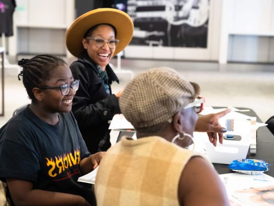 Copyright 2024 Digital Bridges International. All rights reserved. Founder Connie Capiotis. Three smiling people engaged in a lively discussion at a workshop.