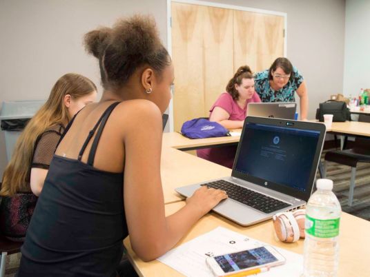 Copyright 2024 Digital Bridges International. All rights reserved. Founder Connie Capiotis. Female students actively engaged in a collaborative classroom setting, taught by Connie.